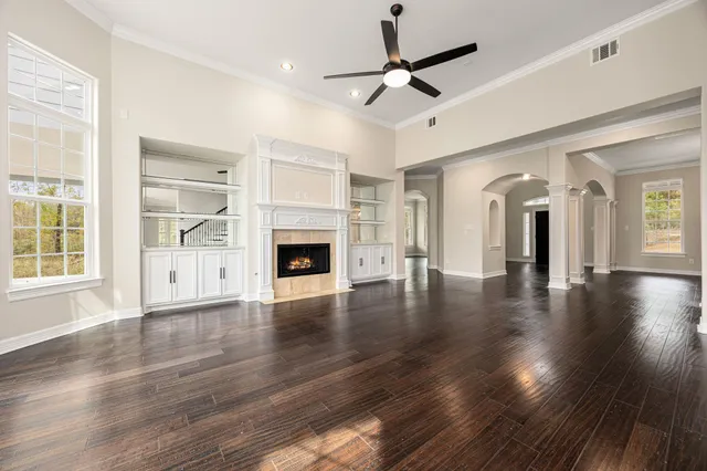 an empty room with wooden floor fireplace and windows