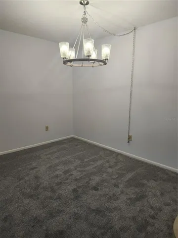 a view of a room with a chandelier fan and wooden floor