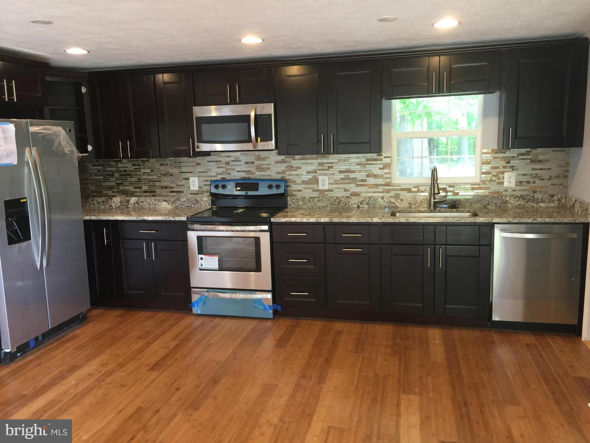 a kitchen with stainless steel appliances granite countertop a stove a sink and a refrigerator