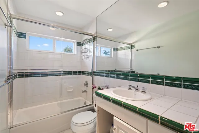 a bathroom with a granite countertop sink a toilet a mirror and bathtub