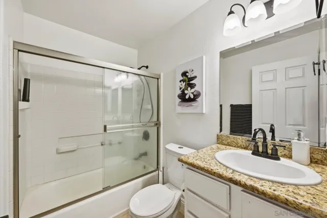 a bathroom with a granite countertop sink toilet and shower