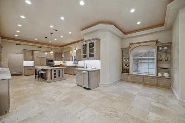 a large white kitchen with a large counter top stainless steel appliances and cabinets