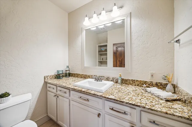 a bathroom with a granite countertop sink a toilet and mirror