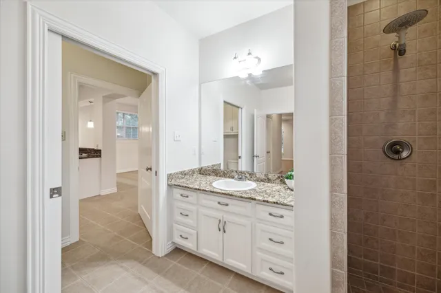 a spacious bathroom with a granite countertop sink a mirror and a shower