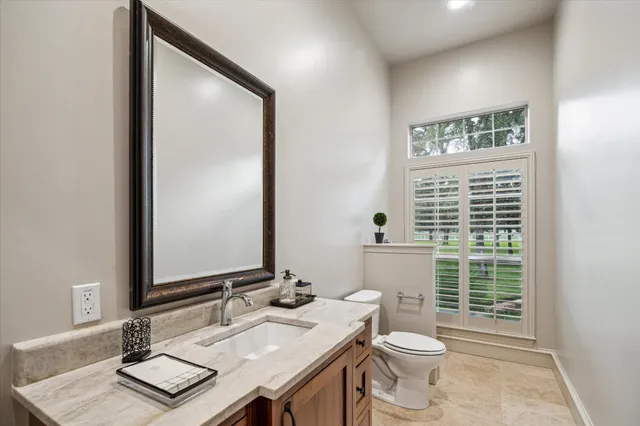 a bathroom with a granite countertop sink toilet and mirror