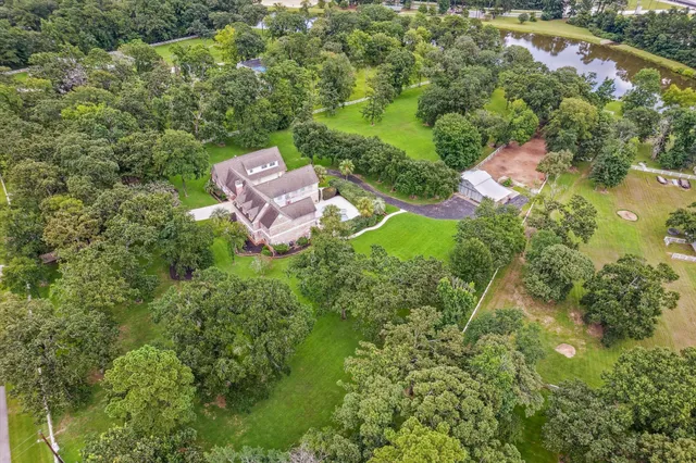 an aerial view of residential house with outdoor space and trees all around