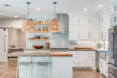 a kitchen with kitchen island granite countertop a sink a counter space appliances and cabinets