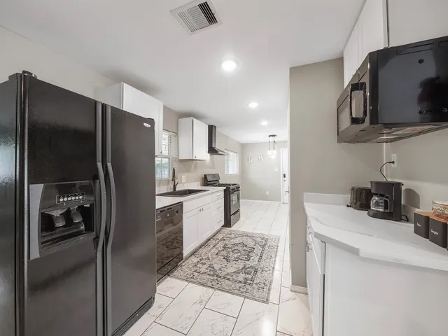 a kitchen with stainless steel appliances kitchen island granite countertop a refrigerator and a sink