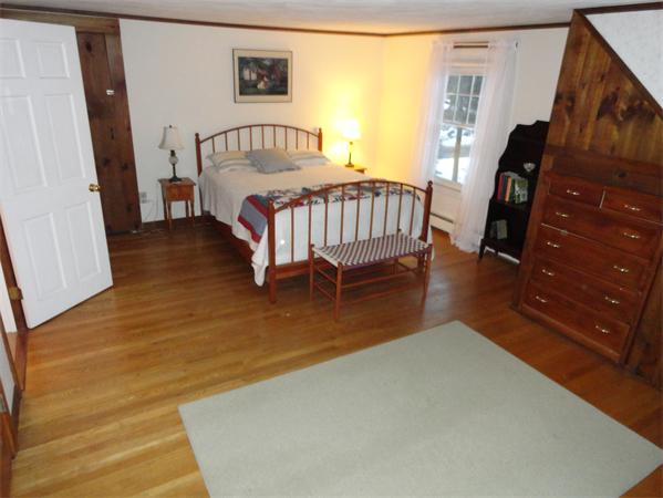 23 Hiley Brook Road Stow, MA 01775 - Photo 6 of 6 a bedroom with a bed next to a window with a flat tv screen on table and a window
