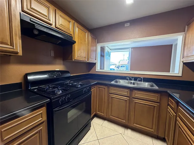 a kitchen with granite countertop a stove sink and cabinets