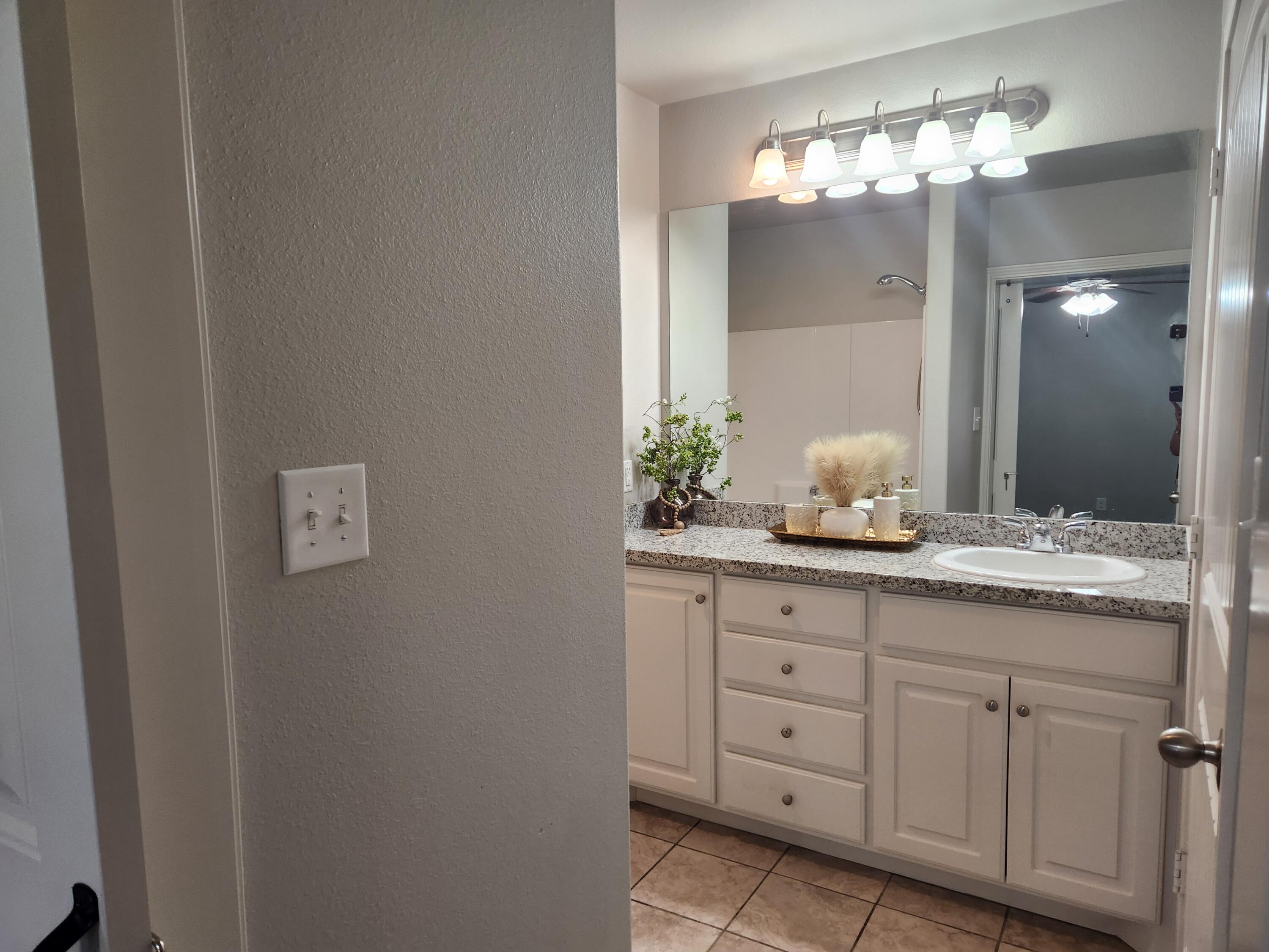 8702 13th Street Lubbock, TX 79416 - Photo 8 of 25 a bathroom with a granite countertop sink and a mirror