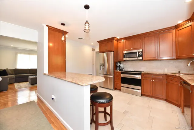 a kitchen with stainless steel appliances kitchen island granite countertop a stove a sink and a refrigerator