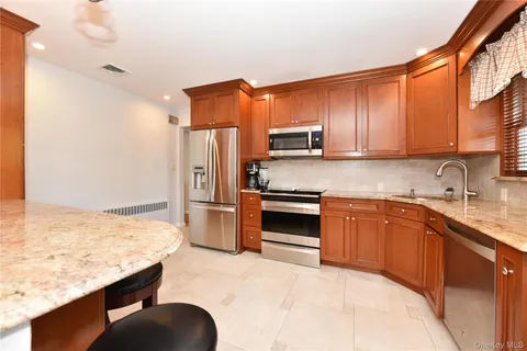 a kitchen with stainless steel appliances granite countertop a sink refrigerator and cabinets