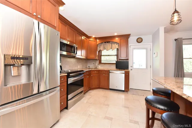 a kitchen with stainless steel appliances kitchen island granite countertop a stove and a refrigerator