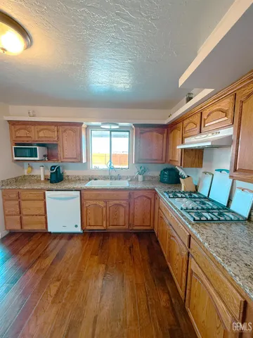 a kitchen with stainless steel appliances granite countertop a stove a sink and a wooden floors