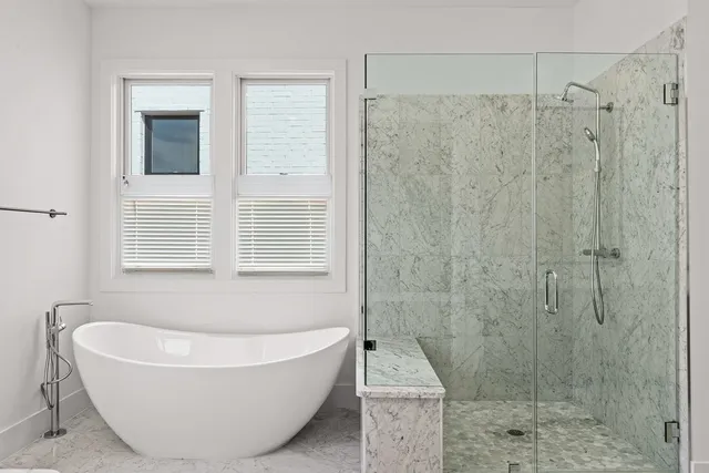 a bathroom with a tub a window and a shower