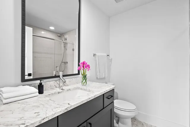 a bathroom with a granite countertop sink mirror and toilet