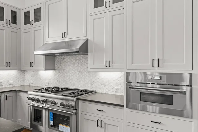a kitchen with granite countertop white cabinets and stainless steel appliances