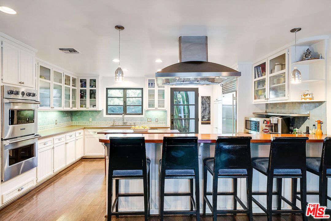 11670 Duque Drive Studio City, CA 91604 - Photo 11 of 48 a kitchen with stainless steel appliances granite countertop a stove a refrigerator a dining table and chairs with wooden floor