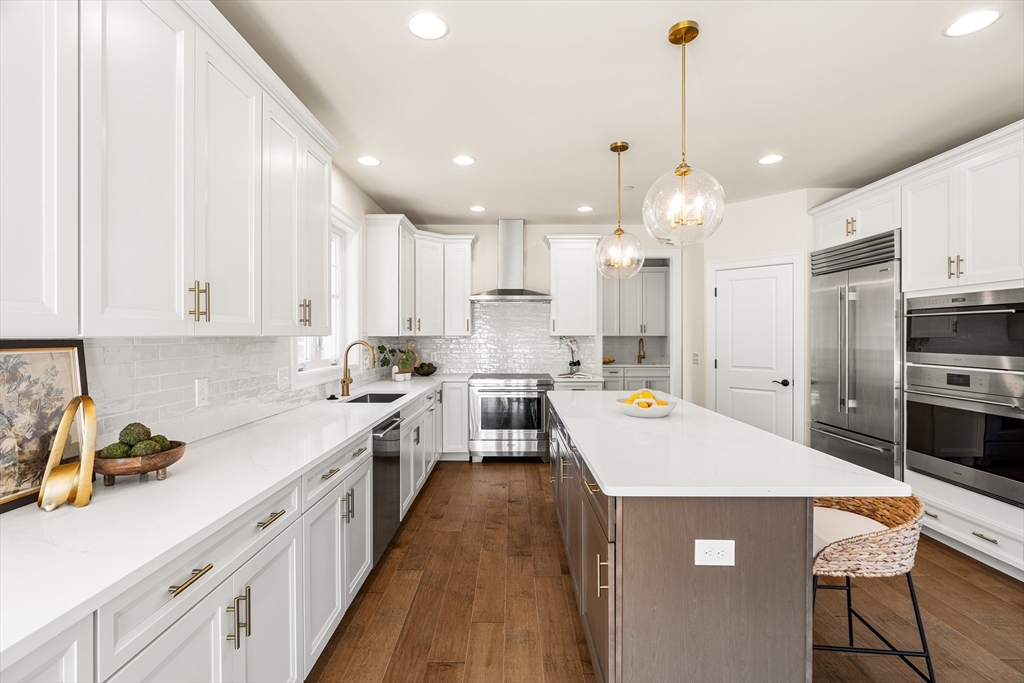 24 Rookery Lane, Unit 6 Concord, MA 01742 - Photo 3 of 41 a kitchen with kitchen island a stove a sink a refrigerator and white cabinets with wooden floor