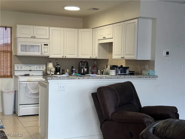 a kitchen with stainless steel appliances granite countertop a refrigerator a stove a sink and white cabinets