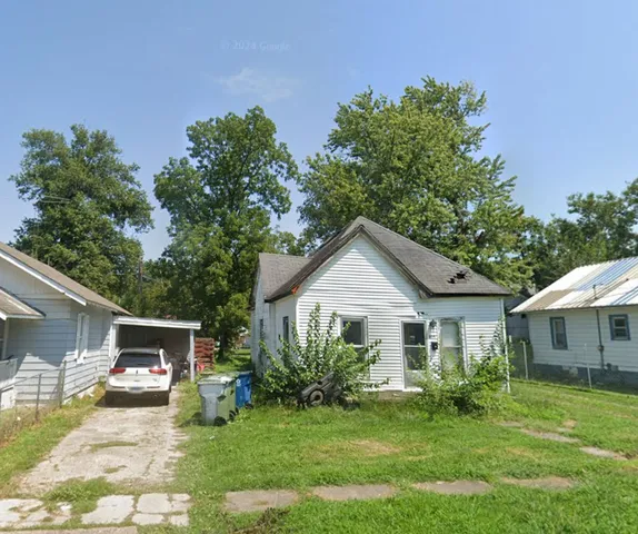 a front view of a house with a garden and trees