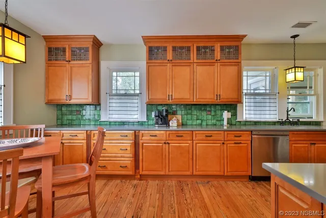 a kitchen with stainless steel appliances granite countertop a refrigerator a stove and a sink with wooden floor