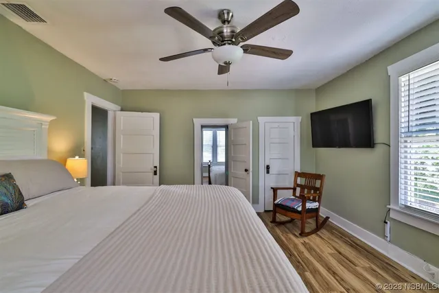 a view of a white house with large trees and wooden fence