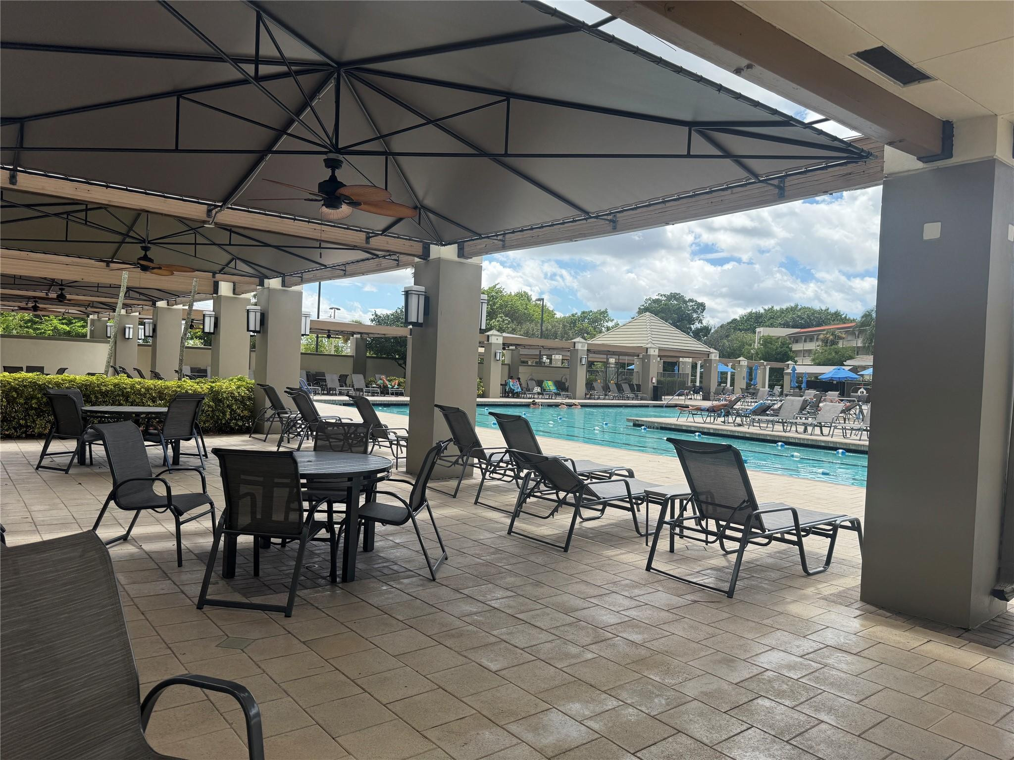 3302 Aruba Way, Unit M1 Coconut Creek, FL 33066 - Photo 38 of 58 a outdoor space with lots of tables a large window and chairs