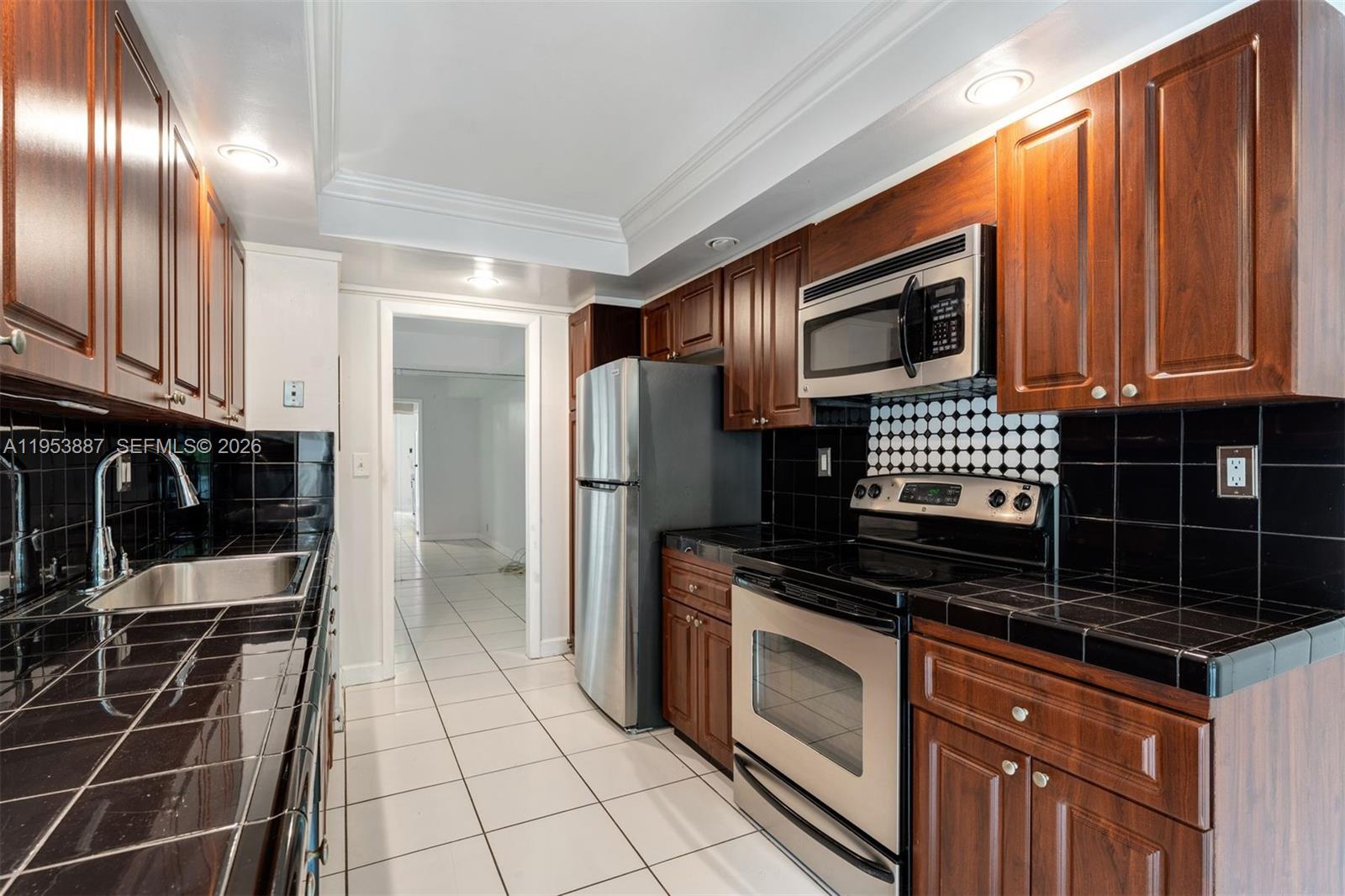 2000 Towerside Terrace, Unit 608 Miami, FL 33138 - Photo 14 of 44 a kitchen with granite countertop a stove a sink and a refrigerator