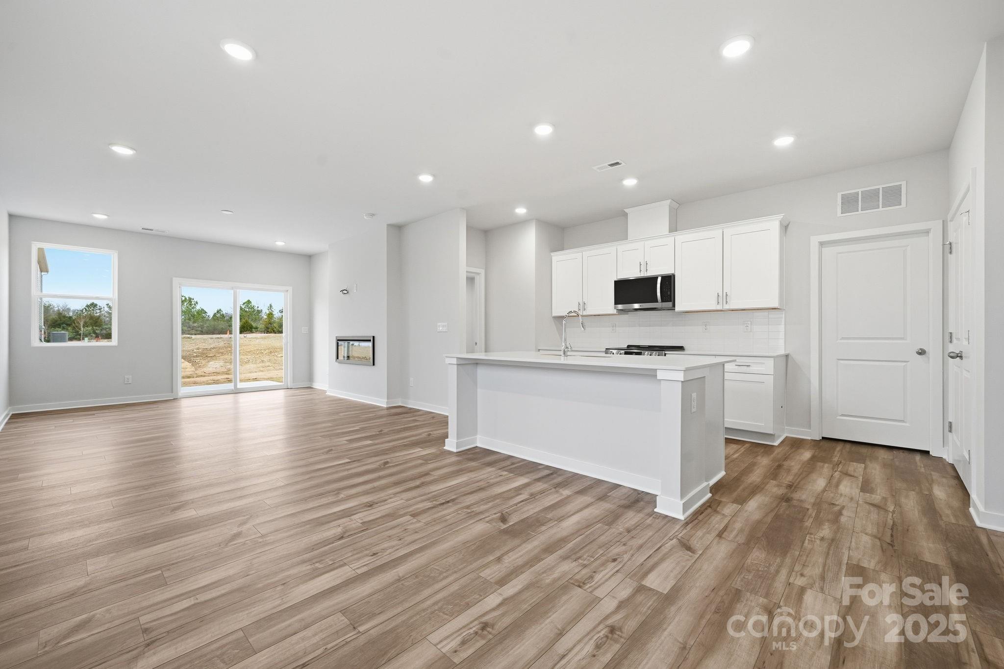 8038 Midas Lane Locust, NC 28097 - Photo 11 of 11 a view of an empty room and kitchen with wooden floor and window