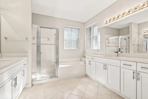 a spacious bathroom with 2 sink bathtub and a mirror