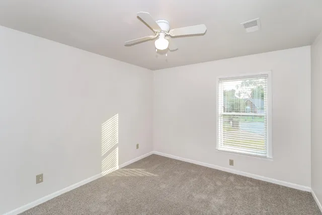 an empty room with windows and fan