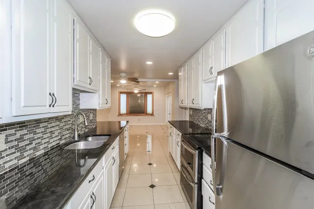 an empty room with wooden floor chandelier and windows