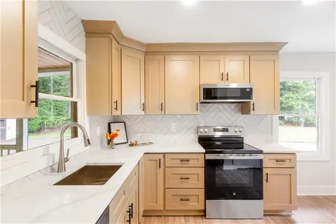 a kitchen with stainless steel appliances kitchen island wooden cabinets a stove a sink and a window