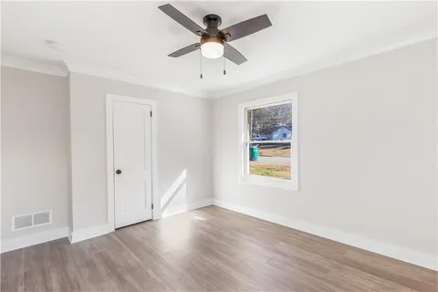 a view of an empty room with window and wooden floor