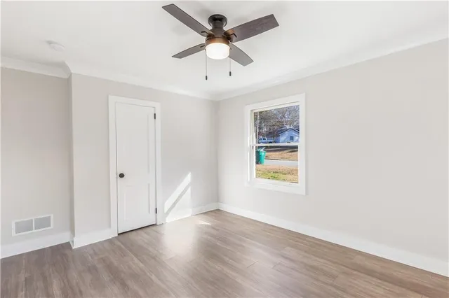 a view of an empty room with window and wooden floor