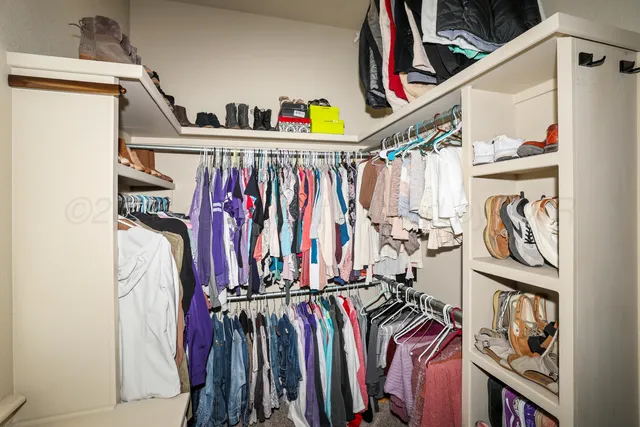 a view of walk in closet with clothes and shoes