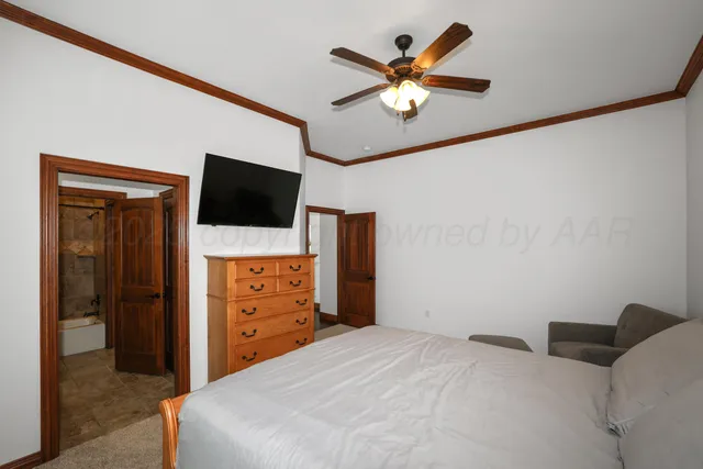 a bedroom with a bed and a flat tv screen on dresser