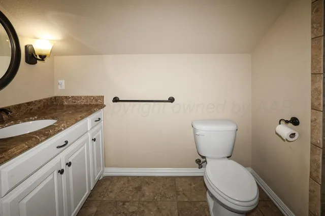 a bathroom with a granite countertop toilet and a sink