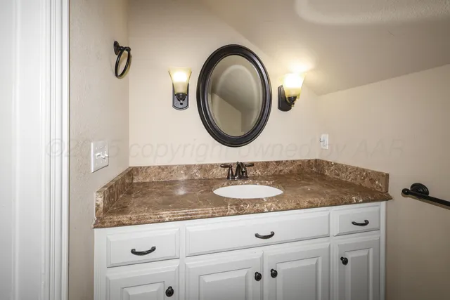 a bathroom with a granite countertop sink and a mirror