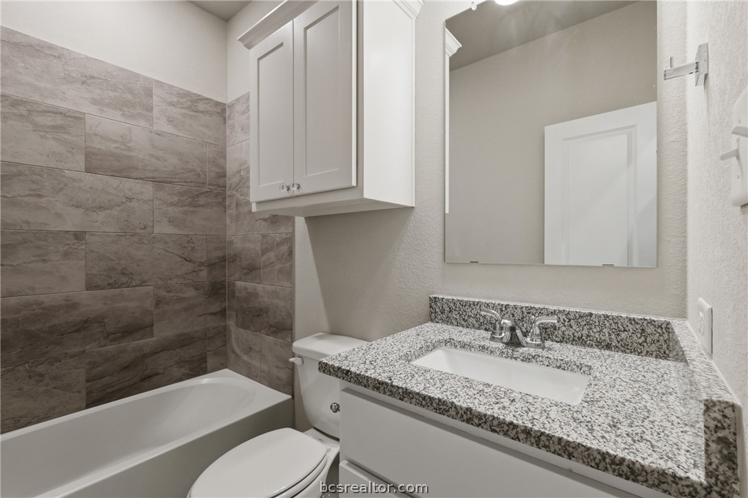 1922 Viva Road Bryan, TX 77807 - Photo 26 of 45 Upstairs full bath featuring granite countertops, painted cabinetry, and a tub/shower combination.