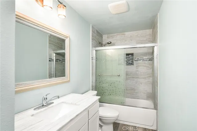 a bathroom with a granite countertop sink a toilet a mirror and shower