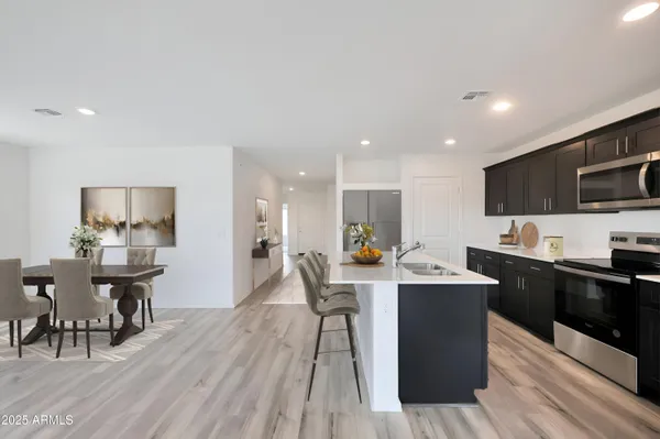 a kitchen with stainless steel appliances kitchen island granite countertop a sink a stove a dining table and chairs