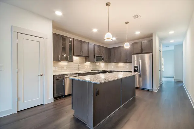 a large kitchen with a large kitchen island white cabinets and stainless steel appliances