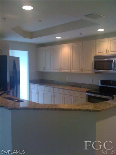 2743 First Street, Unit 1906 Fort Myers, FL 33916 - Photo 2 of 6 a kitchen with granite countertop a stove a sink and a microwave