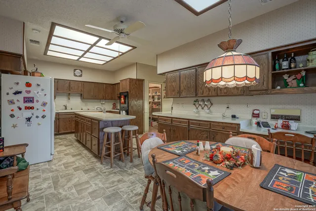 a kitchen with stainless steel appliances granite countertop a sink dishwasher stove a refrigerator a dining table and chairs with the kitchen view