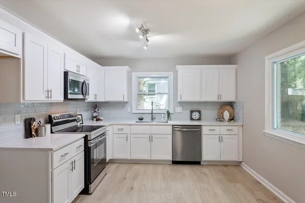 a kitchen with a sink white cabinets and white appliances
