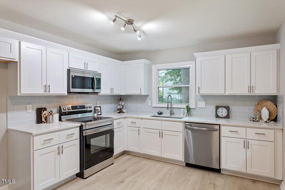 507 Forest Ridge Road Garner, NC 27529 - Photo 6 of 33 a kitchen with white cabinets appliances a sink and a window