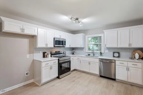 a kitchen with a sink white cabinets and white appliances